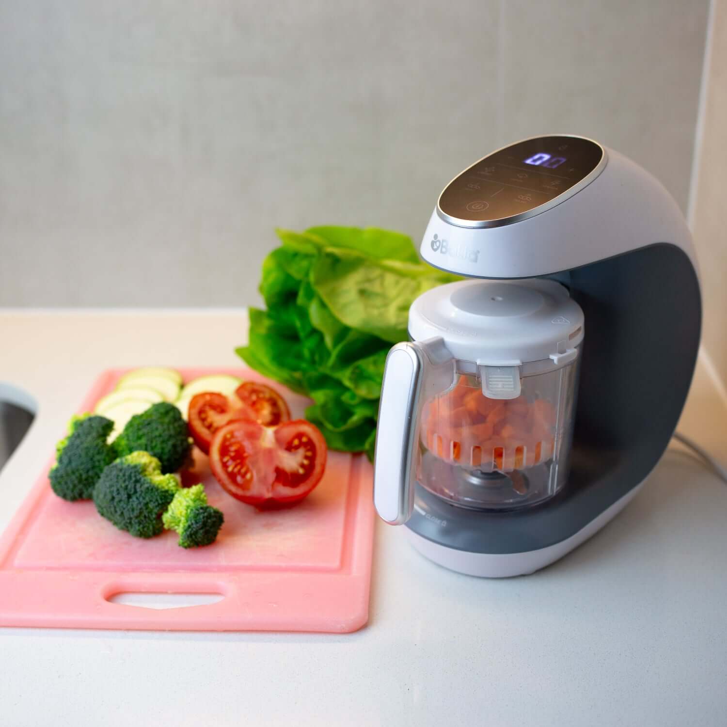 Procesadora de alimentos Multifuncional Balia junto a vegetales frescos en una tabla de cortar.